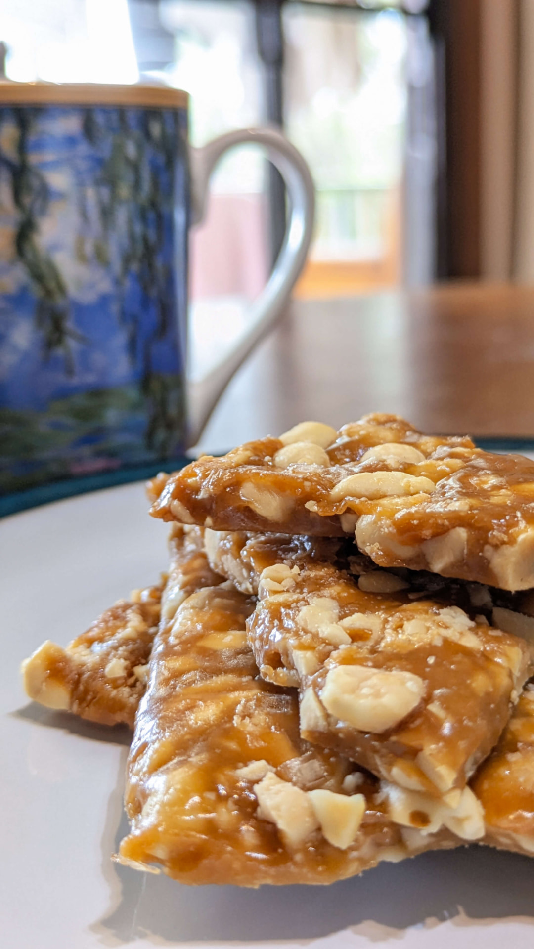 Stack of nutty brittle beside a hand-painted mug