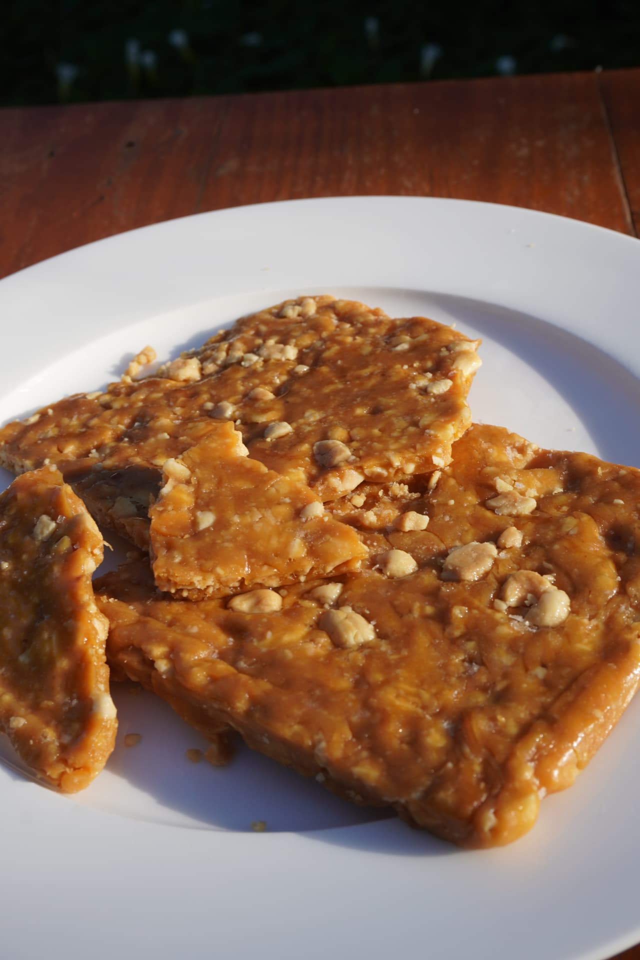 Shards of golden peanut brittle on a white plate